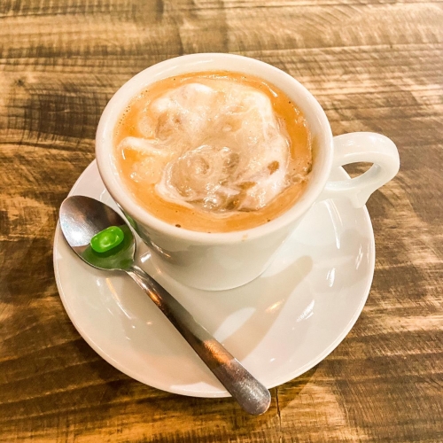 Uma xícara branca com café e um pouco de chantilly misturado com butterscotch