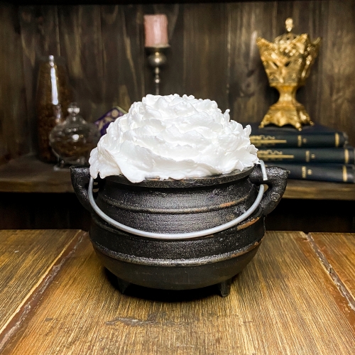 Um mini caldeirão preto, de ferro, com uma cobertura de chantilly