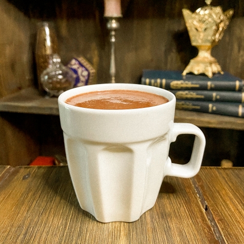 Uma grande caneca branca com chocolate quente dentro.