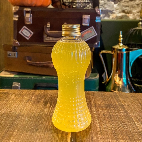Uma garrafinha transparente com líquido amarelo e tampa dourada
