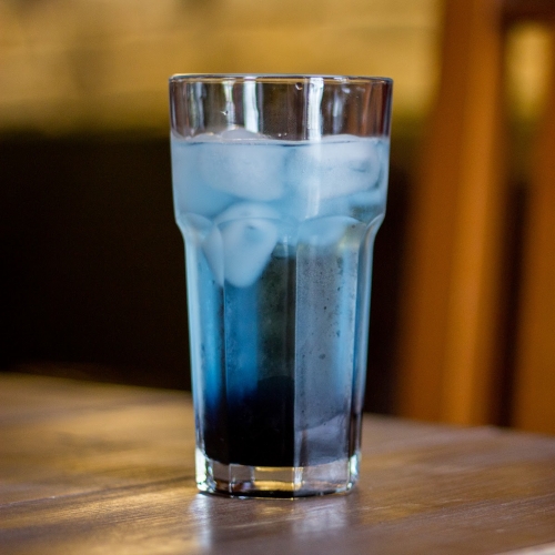 Um copo com líquido azul com gás