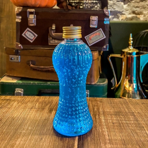 Uma garrafinha transparente com líquido azul e tampa dourada