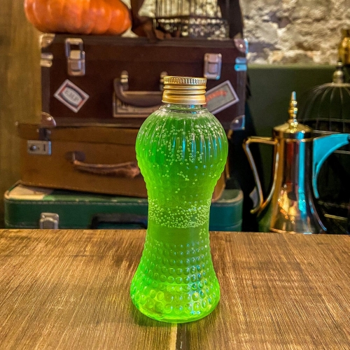 Uma garrafinha transparente com líquido verde e tampa dourada