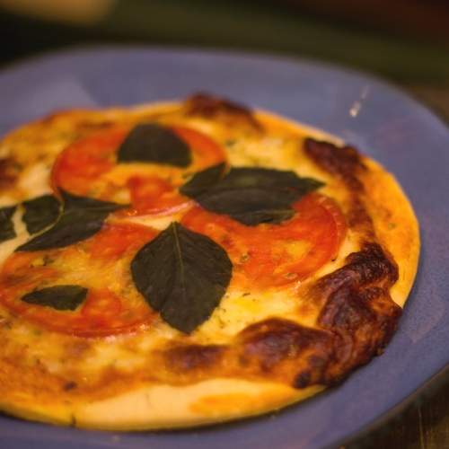 Pizza com queijo, tomate e manjericão em um prato azul