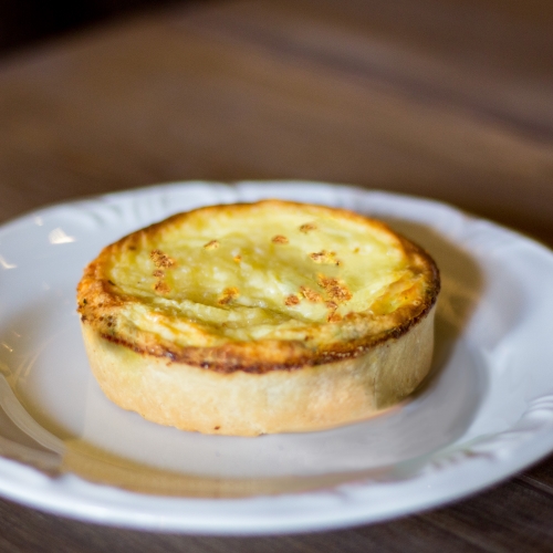 Uma quiche com as bordas douradas do forno, em um prato branco