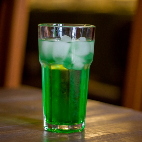 Um copo com líquido verde escuro com gás
