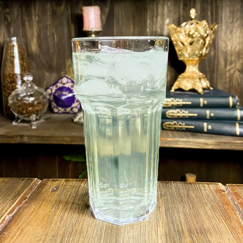Um copo transparente com líquido verde claro