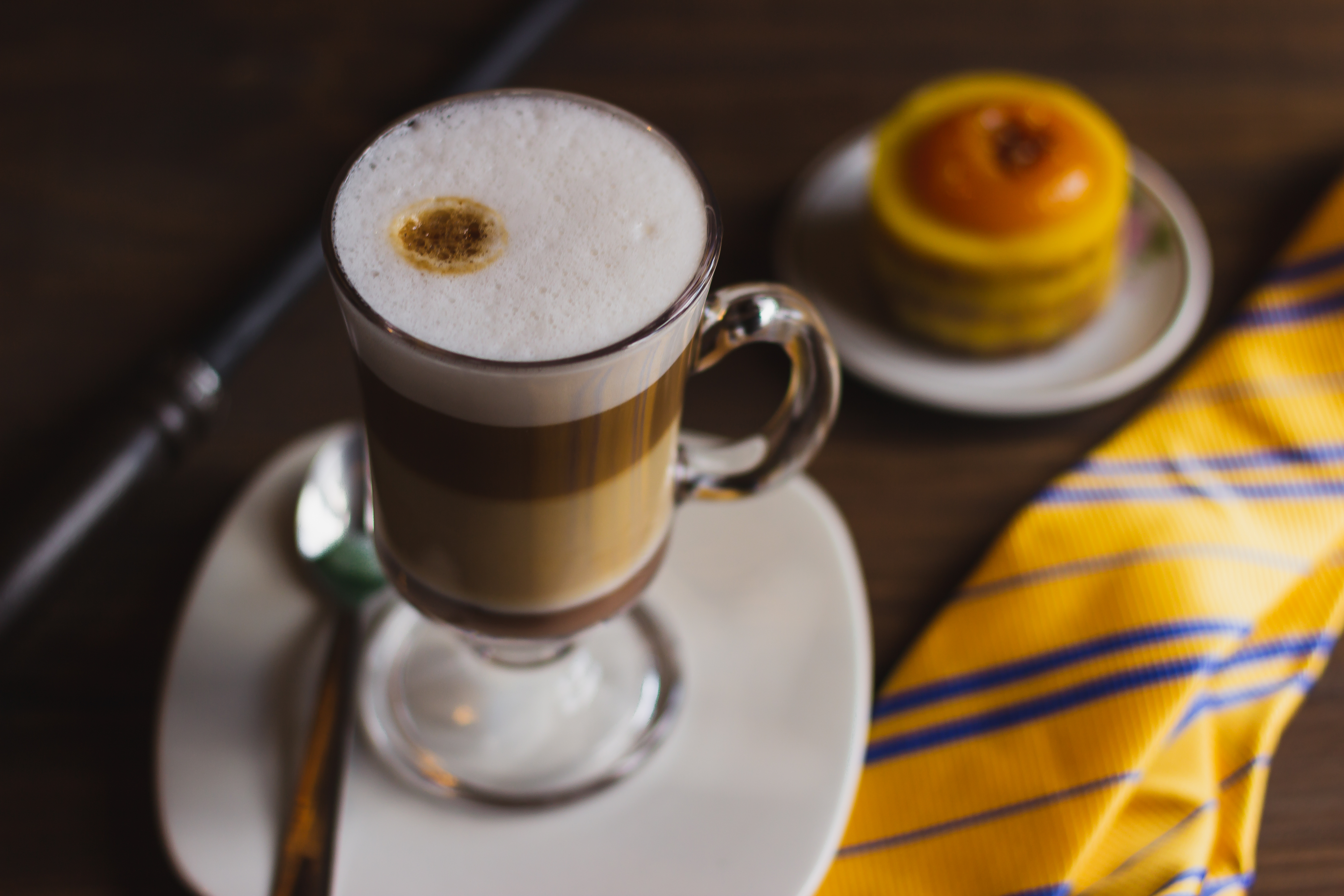 Taça de mocaccino com uma tortinha amarela ao fundo