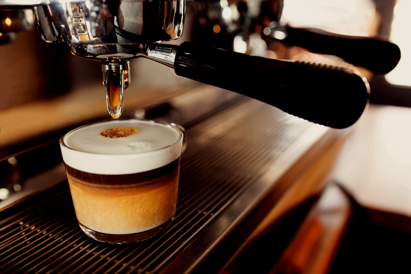 Máquina de café espresso colocando café em uma xícara de capuccino